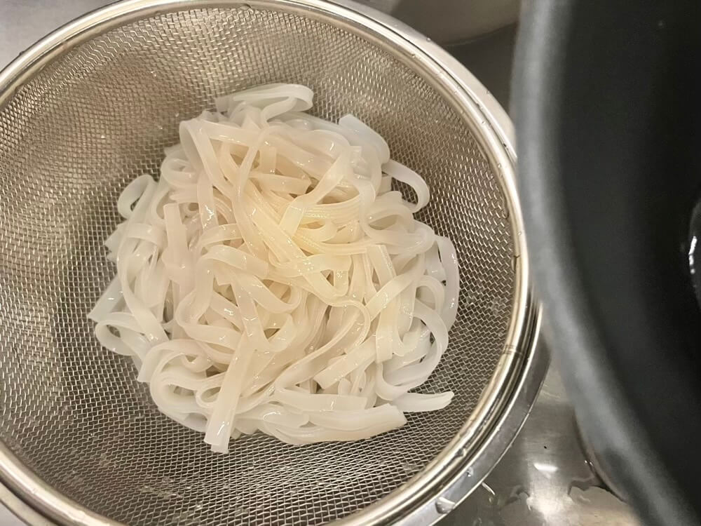 茹で上がったビーフンをザルにあげる