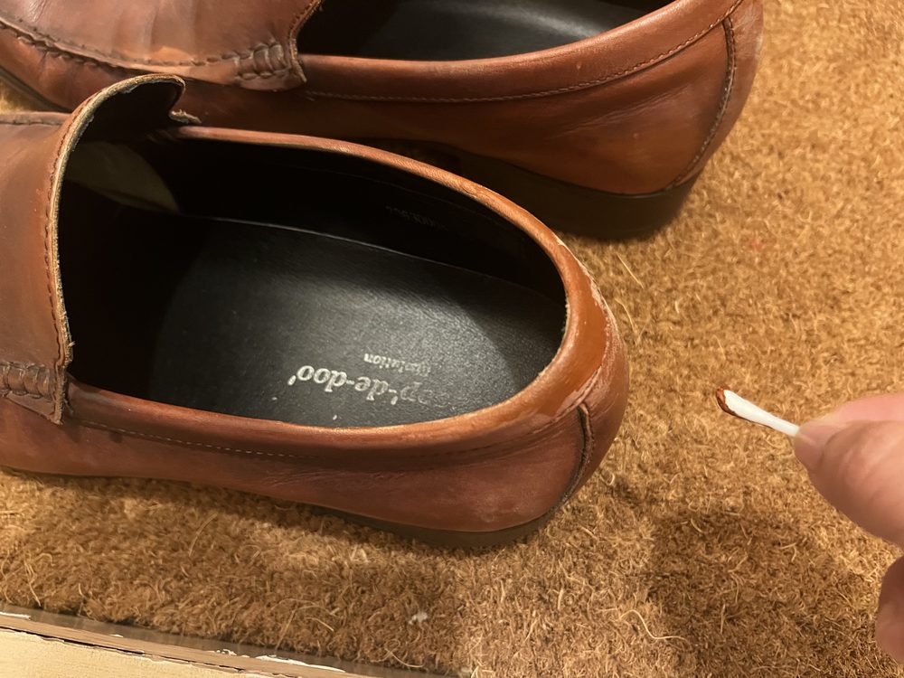 茶色の革靴の履き口の色落ち部分に補修クリームを綿棒で塗っているところ